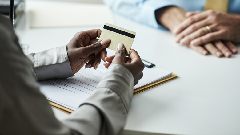A person holding card over a contract on a clipboard