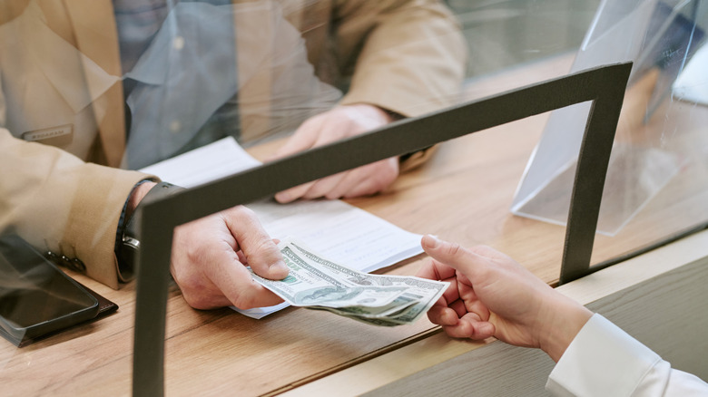 handing cash to a bank teller