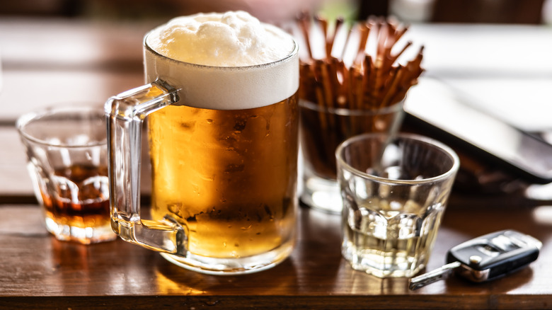 A glass of draft beer and two glasses of hard alcohol, car keys placed next to it.
