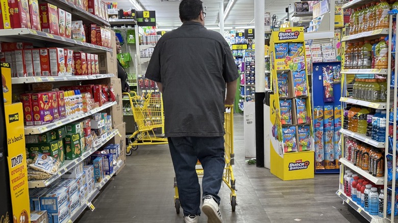 A man pushing a cart through the aisles in Dollar General