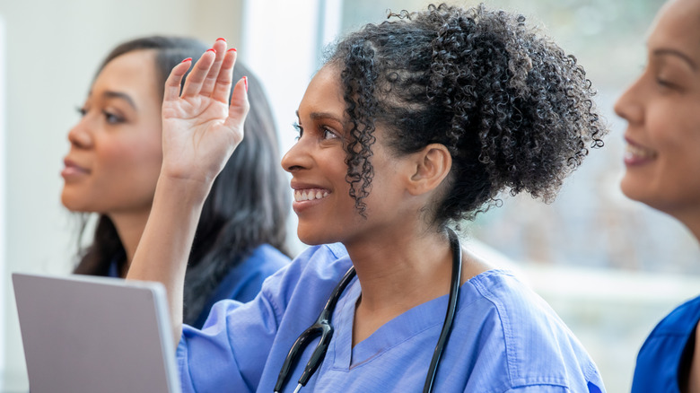 A medical student raising her hand in class.