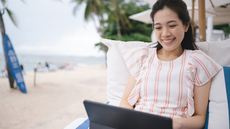 Young woman working on her tablet at a beachside table