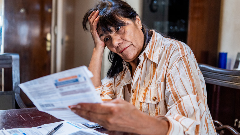 An older woman looking worried as she pays bills