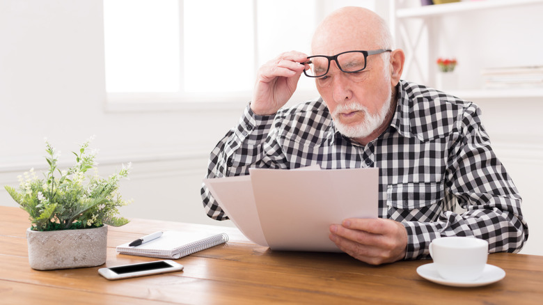 Senior man looking at bills with disbelief