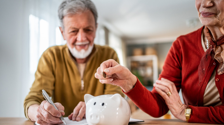 Older couple putting pennies in a piggy bank