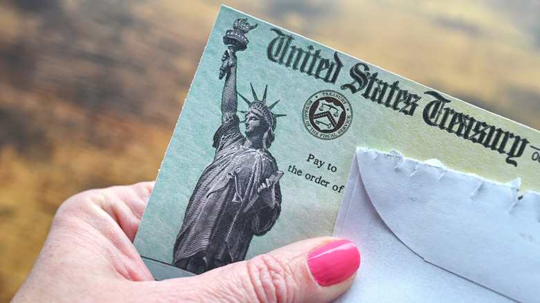 Woman's thumb holding a Social Security check