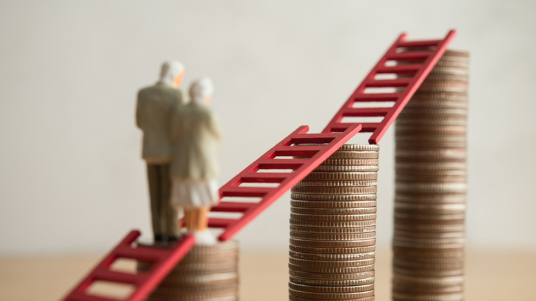 Figurine of mature couple walking climbing ladders over stacks of coins.