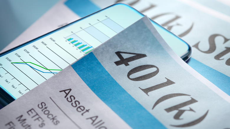 401(k) paperwork on a desk with a smartphone screen displaying graphs.