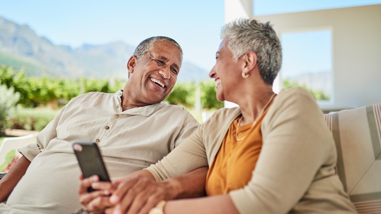 A wealthy older couple smiling outside on vacation