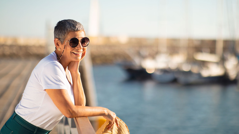 A smiling older woman looking out over a pier