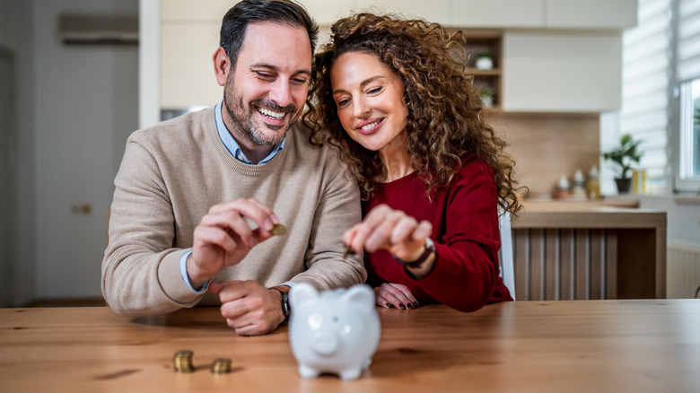 couple putting coins in piggy bank