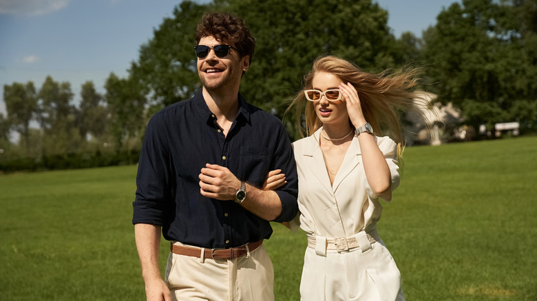 A well dressed affluent couple walking on a gold course.