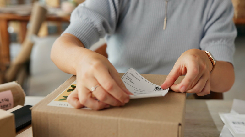Woman adding a label to a box to mail it