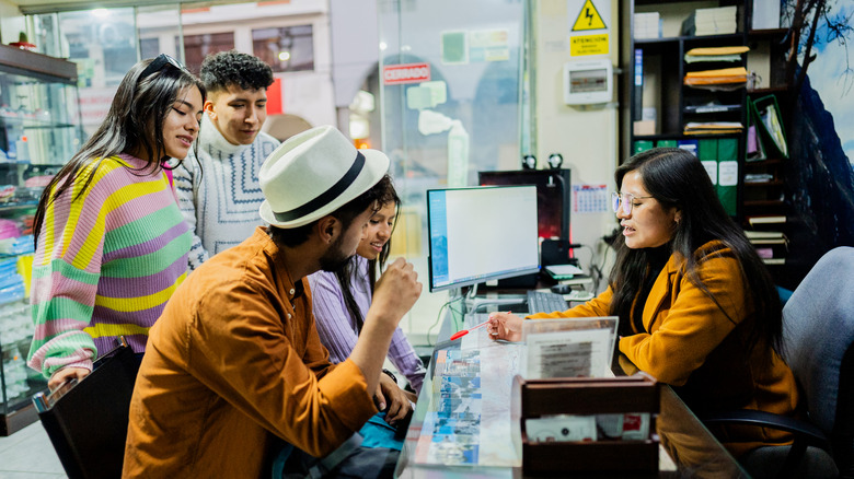 A group of Gen Zers speaking to a travel agent at a travel agency.