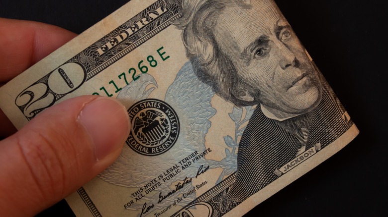 $20 note folded and pinched between someone's fingers