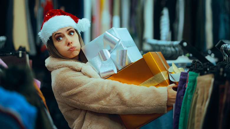 woman wearing santa hat and holding lots of boxes