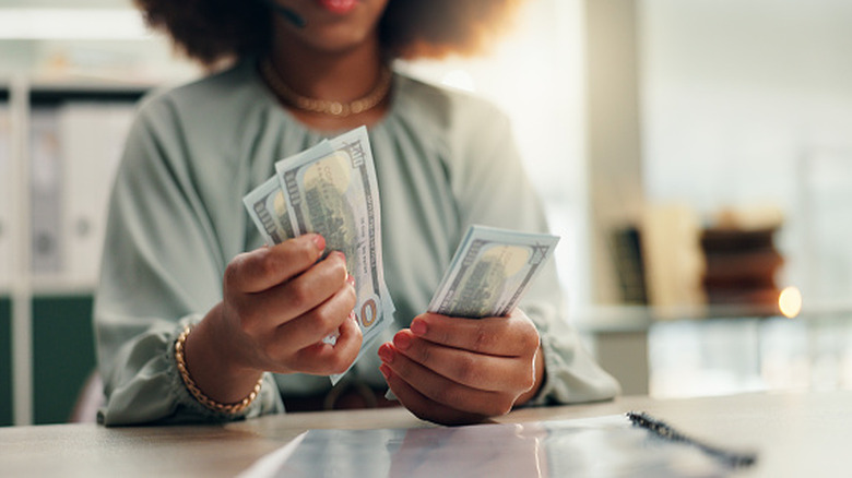 Bottom of woman's head and her hands holding cash