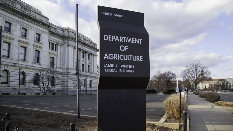 The Department of Agriculture building, with parking lot sign describing it, on a sunny day