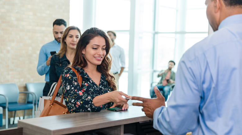 A line of people waiting behind a woman talking to a bank teller