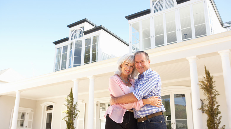 Senior couple standing outside their large dream home