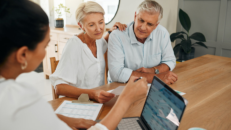 An older couple sitting at a kitchen table talking with a financial planner.