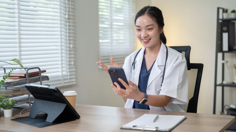 A young doctor smiles as she checks her phone
