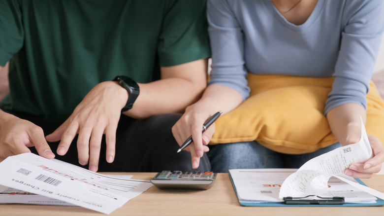 Two people looking over documents with a calculator.