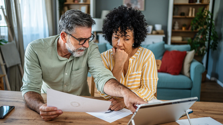 A couple reviews their financial records to save for retirement.