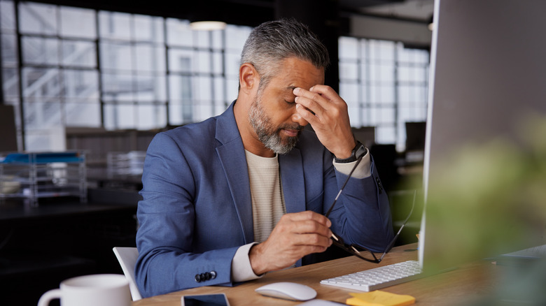 Middle-aged man holding his head while looking at a computer screen