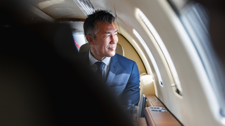 Business man looking out window of private plane