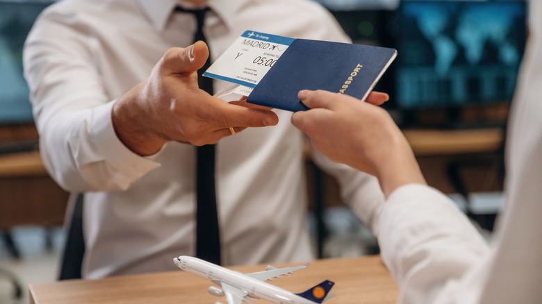Customer handing passport and ticket to airline clerk