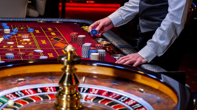 Dealer stacking chips with a roulette wheel in the foreground