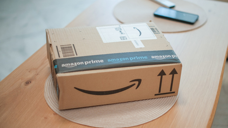 an Amazon box on a coffee table with a phone and a remote control in the background