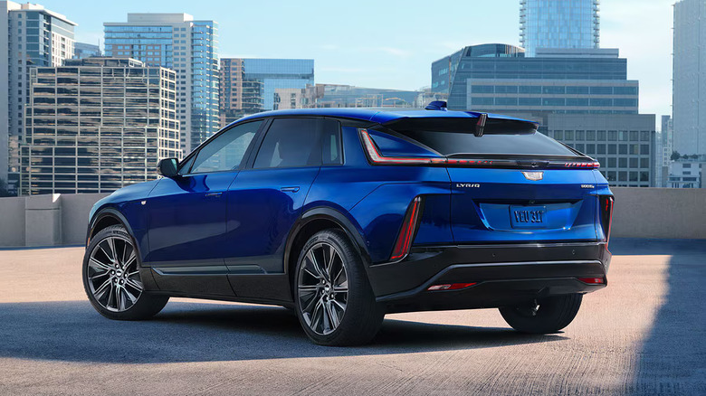 blue 2025 Cadillac Lyriq parked on top level of city parking deck with tall buildings in the background