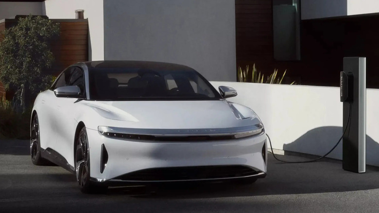 white 2025 Lucid Air charging in front of low, white masonry wall