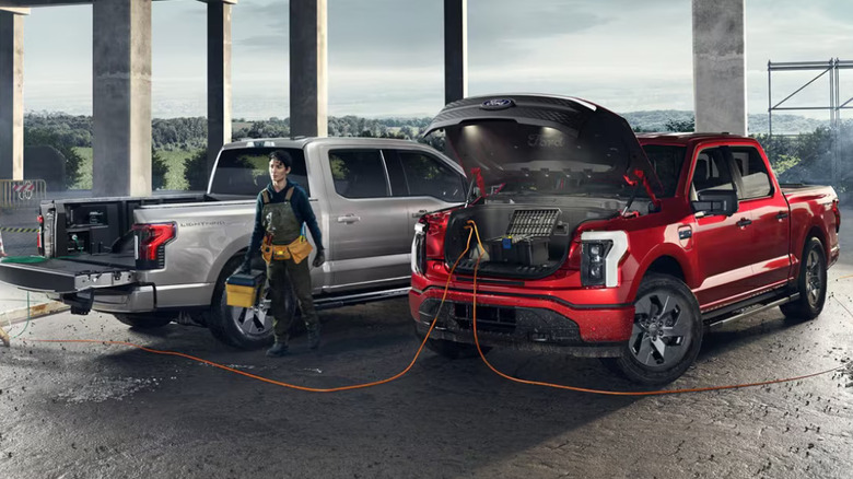 red and silver 2024 Ford F-150 Lightning trucks at worksite sandwiching a worker with toolbox