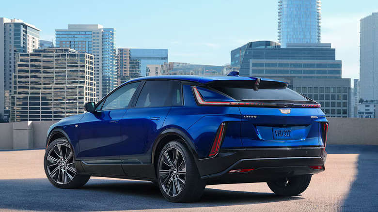 blue 2025 Cadillac Lyriq parked on top level of city parking deck with tall buildings in the background