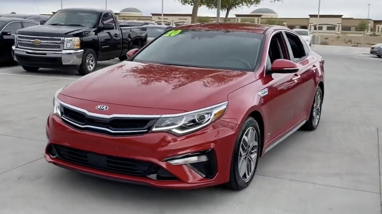 A red 2020 Kia Optima Hybrid on a dealership's lot