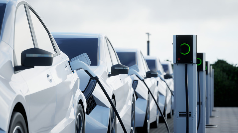 A line of electric and hybrid vehicles plugged into charging stations