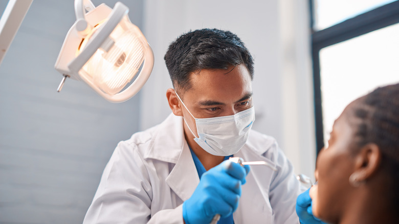 A dentist pointing tools at a patient.