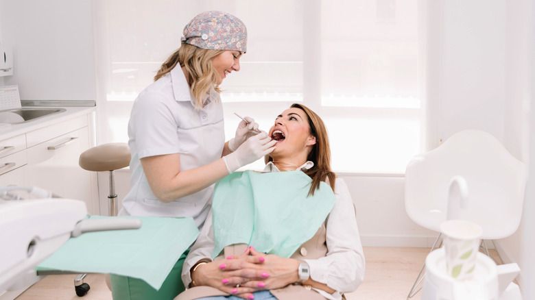A smiling dentist examining a patient's teeth