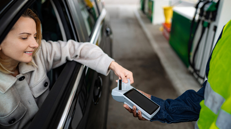 woman paying for something through car window with card