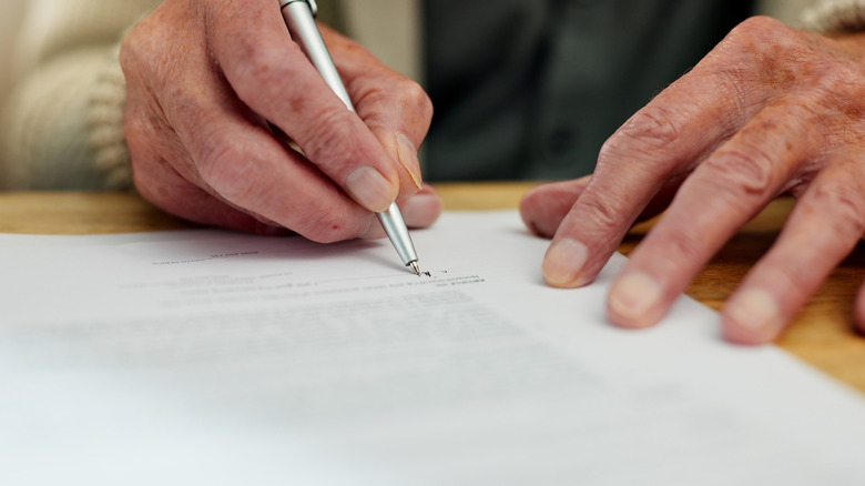 Person signing a document with a pen