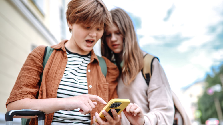 Teenagers with suitcases and a smartphone on the city streets