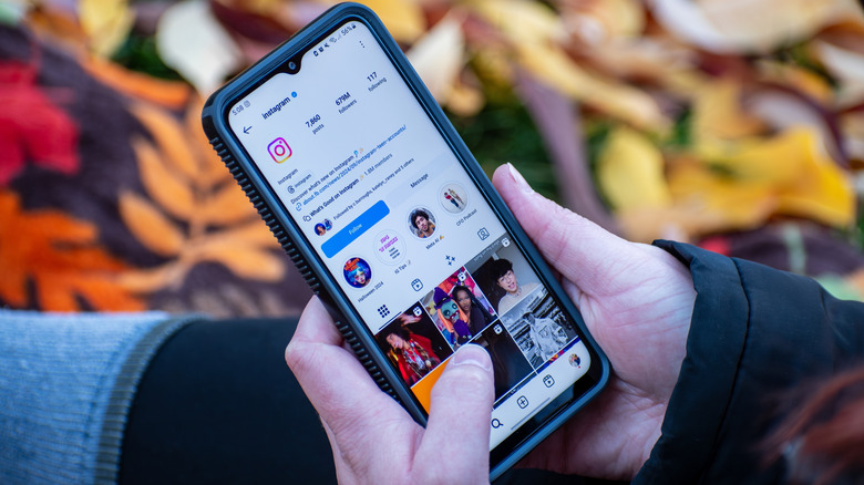Woman holds smartphone with Instagram profile on the screen