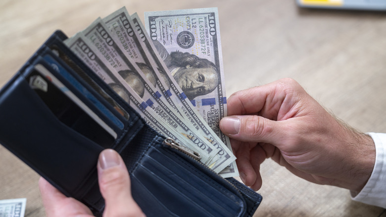 Hands holding a wallet with a small amount of US dollars, close up