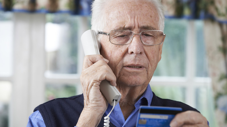 Senior man on the phone while holding his bank card