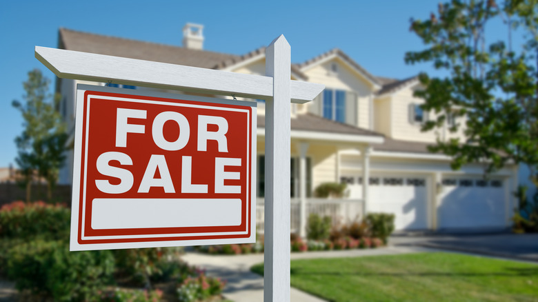 Large residential property with a red "For Sale" sign in the front yard