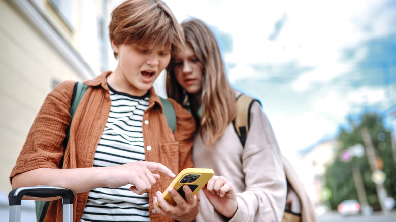 Teenagers with suitcases and a smartphone on the city streets