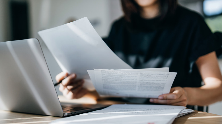 Cropped shot of young Asian woman handling personal banking and finance with laptop at home